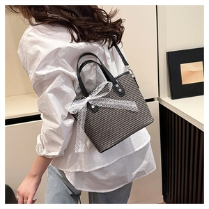 Detail of checkered shoulder bag featuring a white lace bow and round black handle