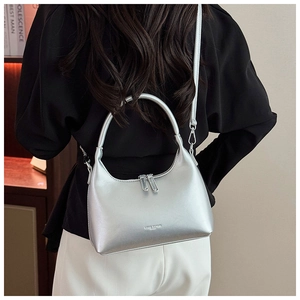 Detail of silver metallic handbag with dual zippers and sleek leather texture for women