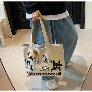Detail of canvas tote bag featuring cute cartoon animal prints and a plush dog charm