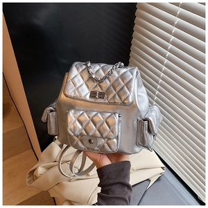 Close-up of a silver quilted backpack featuring a metallic finish and twist-lock detail