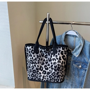 Detail of grey leopard print tote bag with black canvas straps on a metal display stand