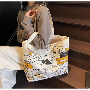 Detail of cute cat pattern printed on durable off-white canvas tote bag held by model