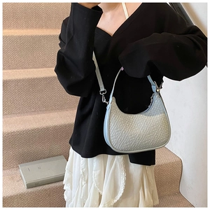 Detail of light blue hobo bag with crocodile texture worn by model on stairs