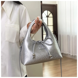 Close-up of metallic silver crescent bag with bow detail and black-white striped lining