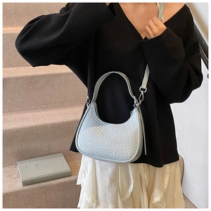 Detail of light blue crescent bag with crocodile texture and detachable silver hardware