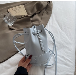 Gros plan sur un sac seau bleu clair avec cordon et détails de ceinture en métal