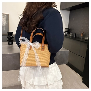 Detail of hand-woven straw bag with elegant white lace bow and brown leather handles
