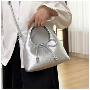 Detail of silver metallic bag featuring pleat texture and delicate bow decoration