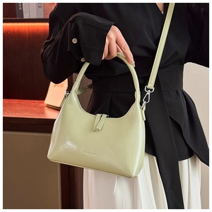 Detail of light green crescent handbag with polished leather and logo on a model