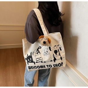 Detail of white canvas tote bag with cartoon cat dog prints and plush puppy charm