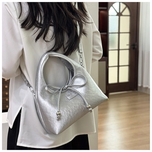 Silver bow shoulder bag with pleated texture and metallic logo detail on a model