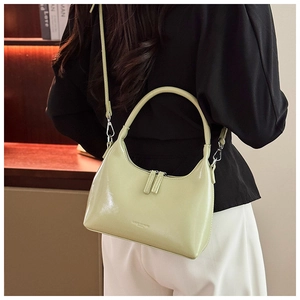 Detailed back view of a light green hobo bag worn crossbody by a model in home setting