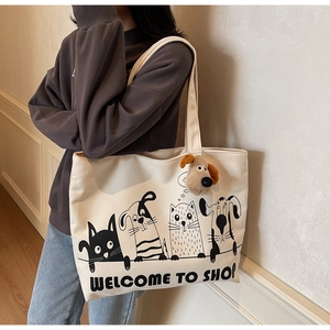Detail of canvas tote bag showing plush puppy charm and cartoon cat dog illustration