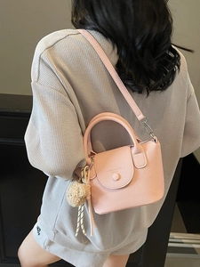 Pink lychee grain bucket bag with teddy bear charm shown as a crossbody bag on model