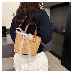 Detailed back view of a woven straw bag with lace bow and leather trim on a model