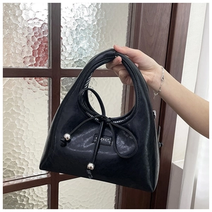 Detail of black faux leather underarm bag with bow tie and silver beads