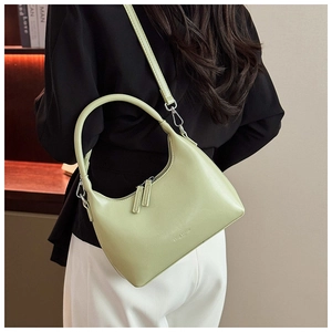 Detailed close-up of a light green crescent leather bag with double gold zippers