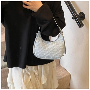 Fashionable light blue crescent bag with crocodile pattern worn by a model on stairs
