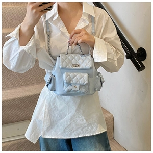 Detail of light blue quilted mini backpack featuring silver chain strap and metal turn-lock