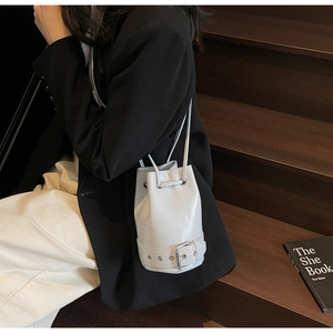 Détail d'un sac seau gris clair minimaliste avec cordon et boucle sur la bandoulière