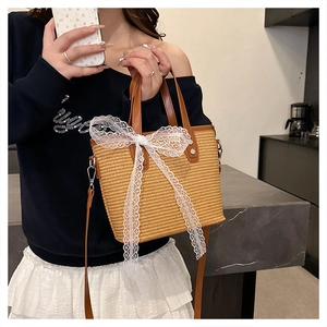 Detail of woven straw handbag featuring a white lace bow and elegant pearl accents