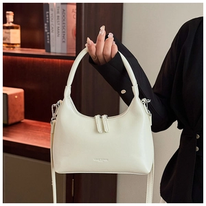 Detailed view of cream hobo shoulder bag with dual zipper and branding on smooth faux leather