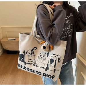 Detail of off-white canvas tote bag with cartoon print and plush dog charm on strap