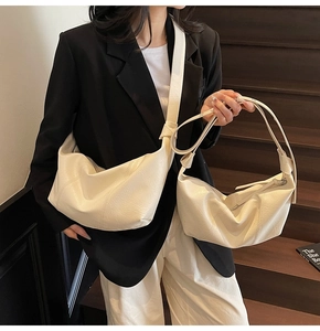 Close-up of stylish cream-colored crescent bags in large and small sizes with wide straps