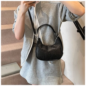 Detailed view of black woven crescent bag with adjustable strap and silver zipper hardware