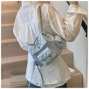 Detail of light blue quilted mini backpack with silver metal chain strap and turn-lock