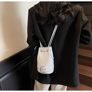 Vue arrière d'un mannequin portant un sac seau blanc avec boucle argentée sur costume noir