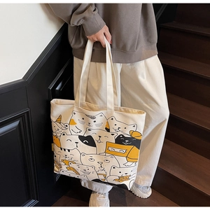 Detail of cartoon cat print canvas tote bag carried by model on wooden stairs