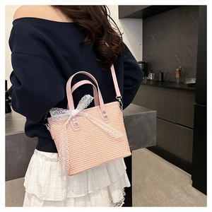 Lifestyle shot of pink woven handbag with white lace bow and adjustable strap