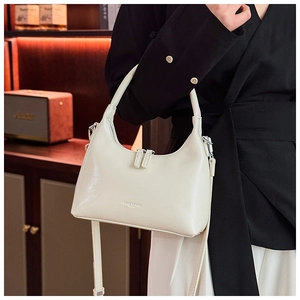 Detail showing creamy white hobo bag with silver logo and adjustable crossbody strap