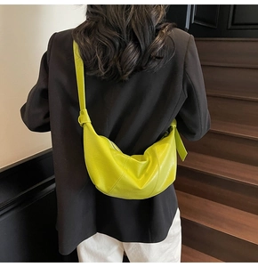 Detail of lime green crescent crossbody bag with knotted strap on indoor steps