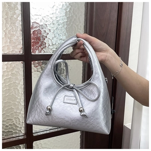Detail of silver metallic crescent bag with bow drawstring and pearl bead accents