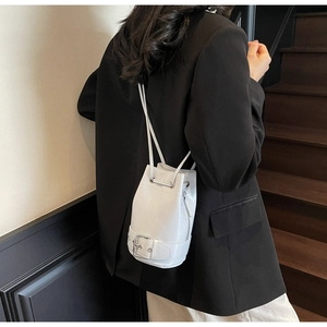 Détail du sac seau gris à cordon avec boucle argentée et texture en similicuir lisse