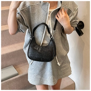 Detail of black woven crescent bag with silver hardware and smooth leather strap