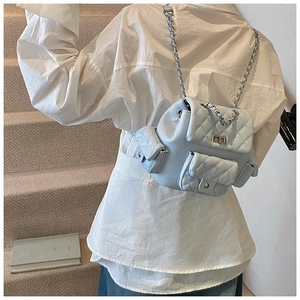 Light blue quilted mini backpack with chain straps worn by model on stairs detail