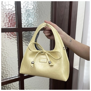 Detail of cream leather bag featuring a tied bow with silver bead and striped lining