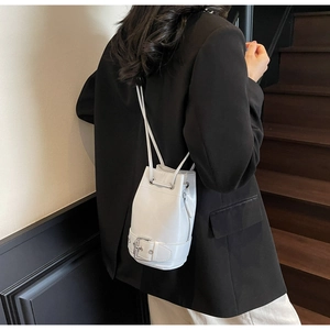 Détail du sac seau blanc avec fermeture à cordon et décor de sangle à boucle métal
