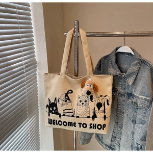 Detail of beige canvas tote with cartoon animal print and plush puppy charm on a hanger