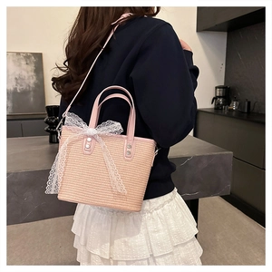 Close-up of pink woven bucket bag with white lace bow and leather handle details