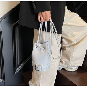 Détail du sac seau bleu-gris clair montrant le cordon de serrage et la boucle métallique décorative