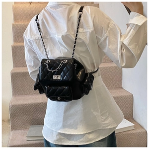 Detailed view of black quilted faux leather mini backpack with silver chain straps