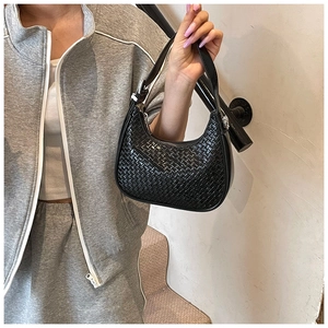 Detail of black woven texture on a minimalist half-moon shoulder bag with zipper closure