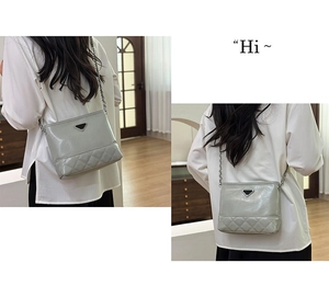 Detail of grey quilted bucket bag featuring a silver chain strap and metal triangle plaque