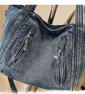 Detailed shot of a blue denim tote bag featuring dual front zippers and vintage texture