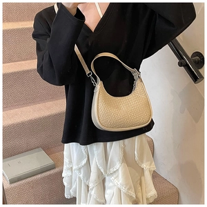 Detail of beige woven half-moon shoulder bag with adjustable strap and silver buckle
