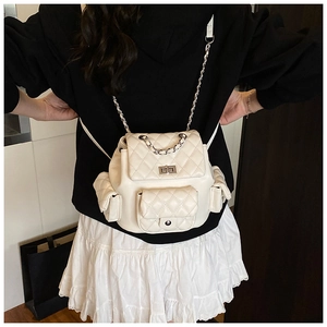 Detail of white quilted mini backpack featuring a silver twist lock and chain strap